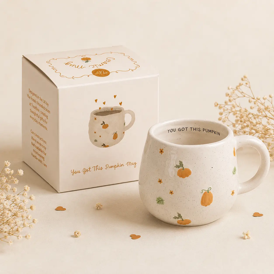 Cream speckled ceramic mug with orange pumpkins, green leaves and 'You Got This Pumpkin' lettering inside the rim, shown beside its matching gift box.